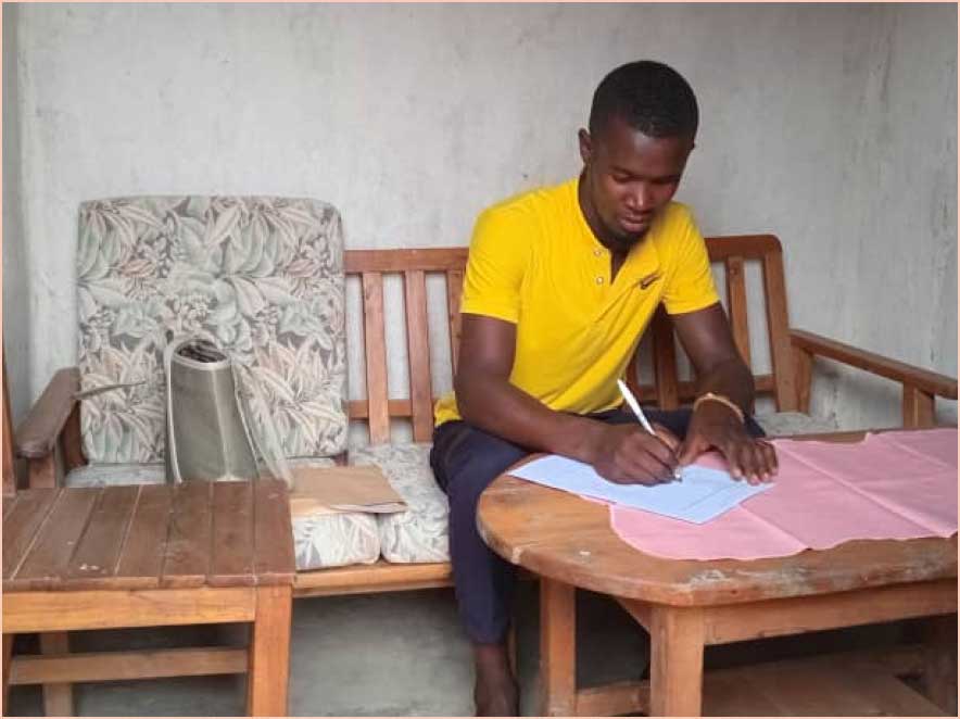 Shema, farmer in Rwanda writing a document